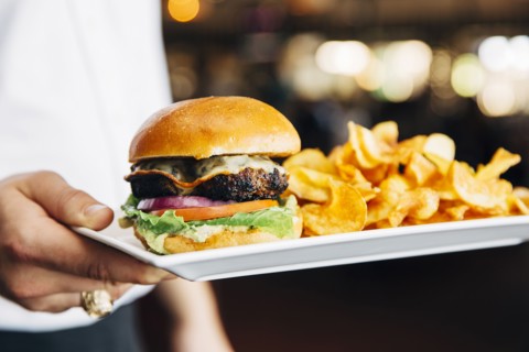 Caucasian waiter carrying cheeseburger and chips in cafe