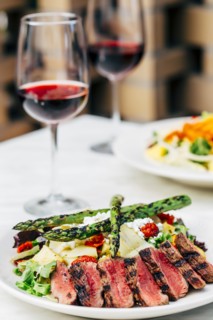 Plate of grilled meat and asparagus salad with wine