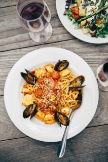 Plates of salad and pasta with wine glasses