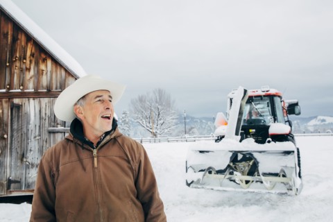 Caucasian farmer and tractor in snowy field