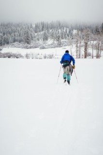 Caucasian woman cross-country skiing in snowy field