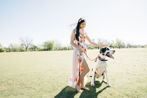 Chinese woman walking dog in field
