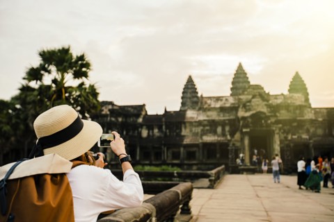 Caucasian tourist photographing Angkor Wat ruins