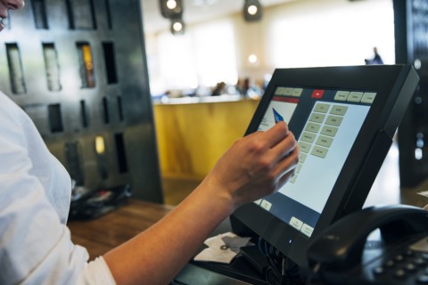 Caucasian cashier using touch screen to process credit card payment