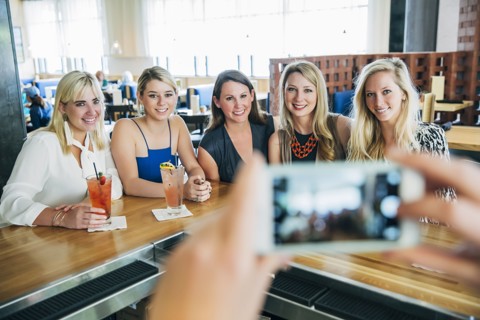 Caucasian bartender taking cell phone photograph of customers