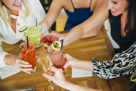 Caucasian women toasting at bar with cocktails
