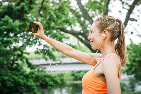 Caucasian woman using earbuds taking selfie