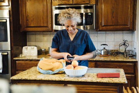 Black woman texting on cell phone in domestic kitchen