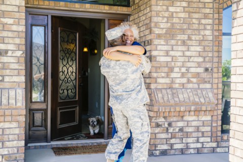 Black soldier hugging wife in doorway