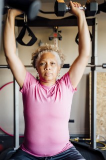 Black woman lifting weights in garage