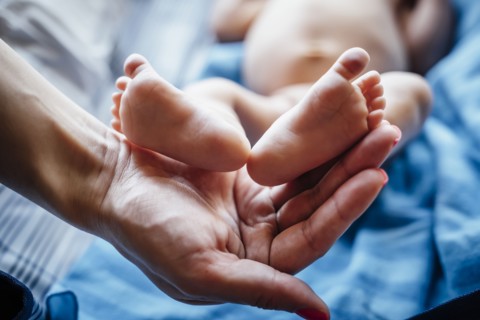 Hispanic woman holding feet of baby boy