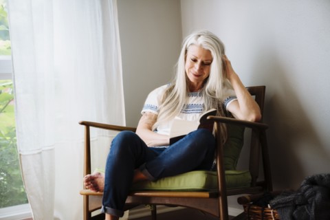 Caucasian woman sitting in armchair reading book