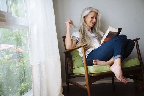 Caucasian woman sitting in armchair reading book