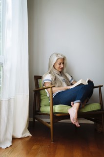 Caucasian woman sitting in armchair reading book