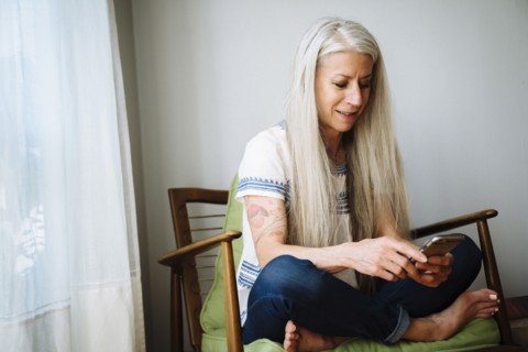 Caucasian woman sitting in armchair texting with cell phone
