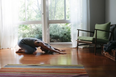 Caucasian woman kneeling on floor stretching