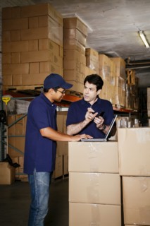 Warehouse workers using laptop and cell phone