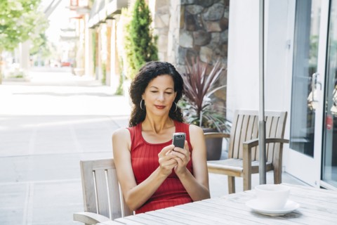 Mixed Race woman texting on cell phone at cafe