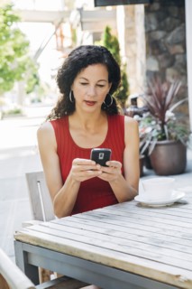 Mixed Race woman texting on cell phone at cafe
