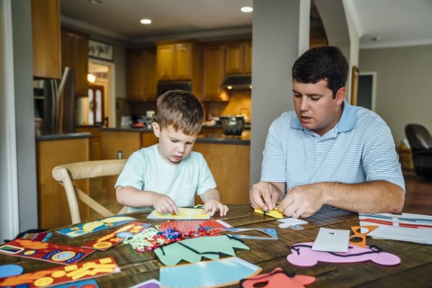Caucasian father and son making masks at table