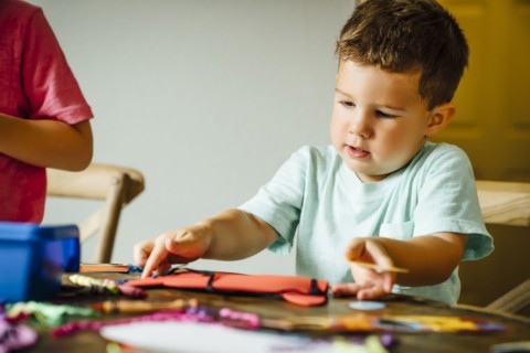 Caucasian boy making mask on table