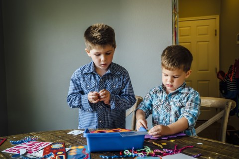 Caucasian boys making masks at table