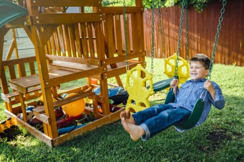 Smiling Caucasian boy n swing in backyard