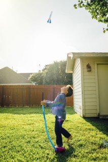 Caucasian boy flying toy rocket in backyard