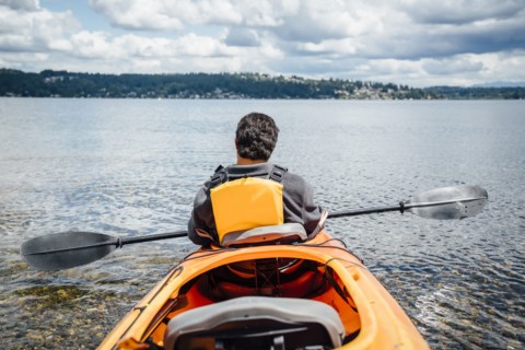 Mixed Rave man sitting in kayak holding paddle