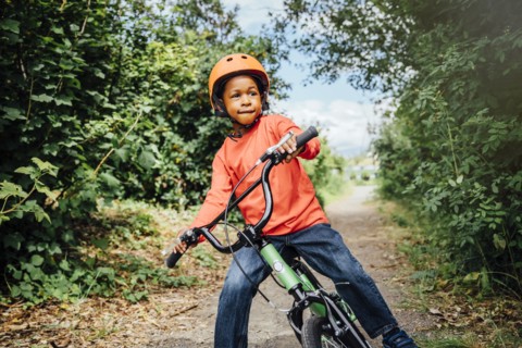 Black boy riding bicycle with helmet