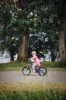 Mixed Race girl riding bicycle with training wheels