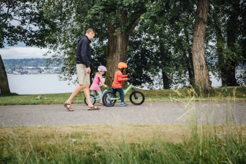 Father watching daughter and son riding bicycles