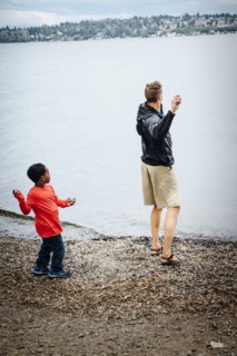 Father and son throwing rocks into river