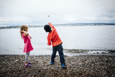 Boy and girl throwing rocks into river