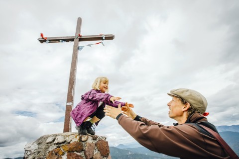 Caucasian father helping daughter on rock at crucifix