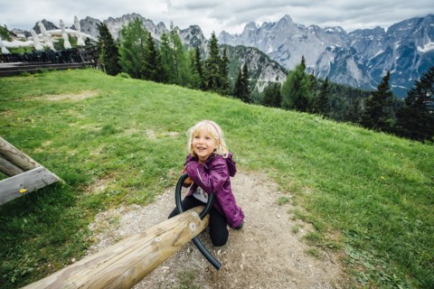 Caucasian girl on seesaw near mountain range