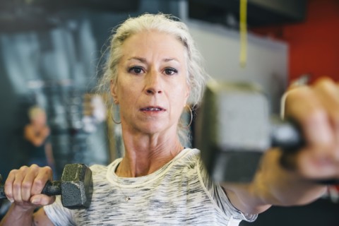 Caucasian woman lifting dumbbells in gymnasium