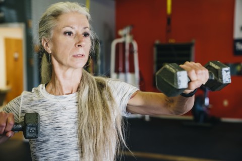 Caucasian woman lifting dumbbells in gymnasium