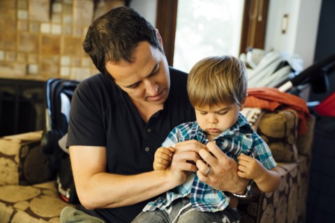 Father buttoning shirt for son