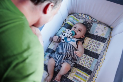 Father watching baby son in crib