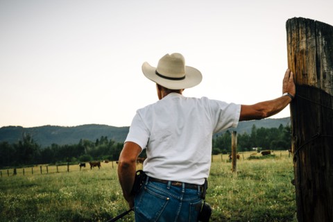 Caucasian farmer leaning on wooden post