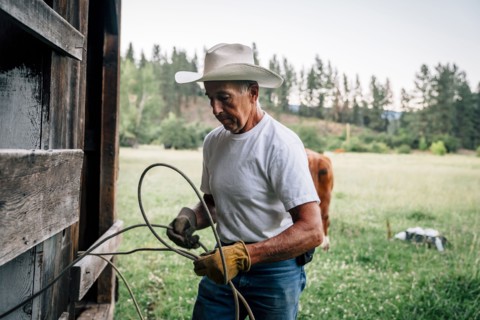 Caucasian farmer tying rope on fence