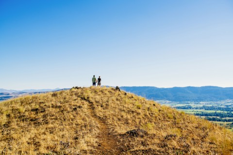 Distant Caucasian couple standing on hill holding hands