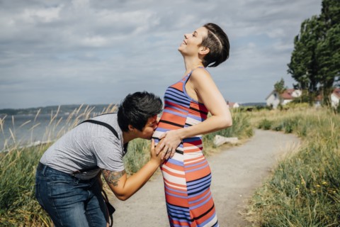 Woman kissing belly of expectant mother
