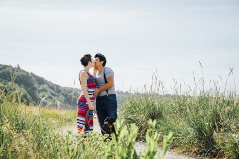 Pregnant lesbian couple kissing on path