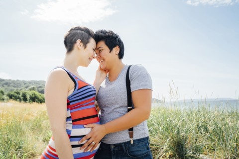 Pregnant lesbian couple hugging outdoors