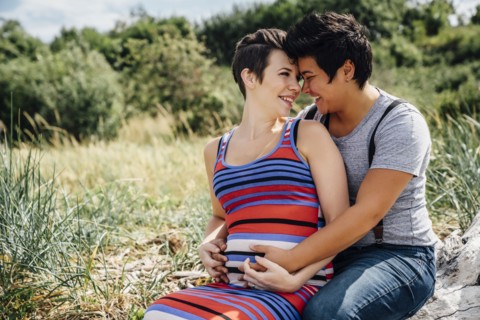 Pregnant lesbian couple rubbing noses outdoors