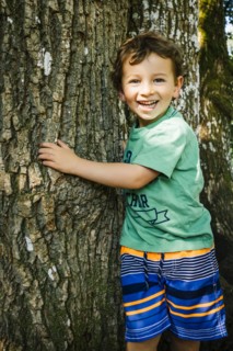 Portrait of smiling Caucasian boy hugging tree