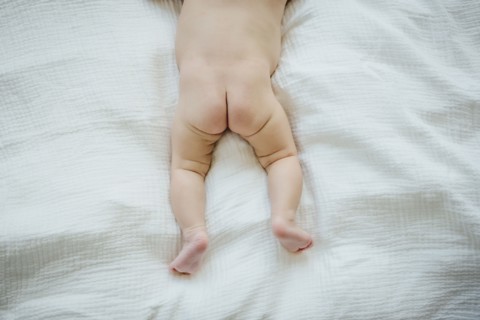 Naked buttocks of Mixed Race baby girl laying on blanket
