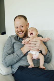 Portrait of smiling father holding crying baby daughter